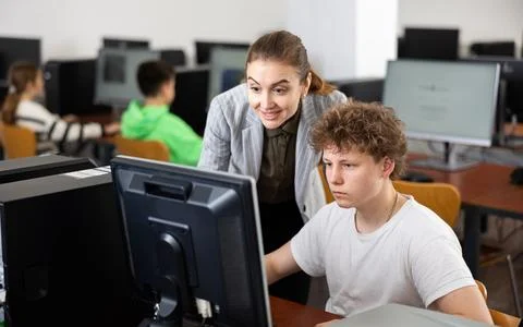 Teacher helping boy to solve computer problem Stockfoto's