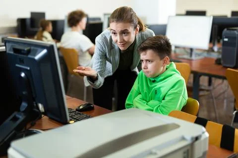 Teacher helping boy to solve computer problem Stockfoto's