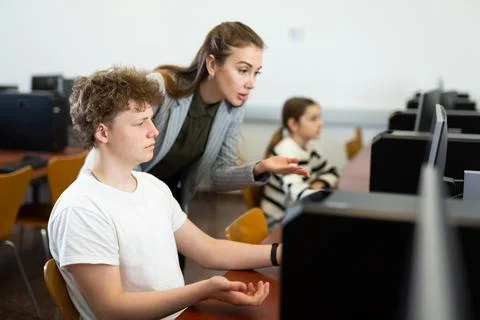 Teacher helping boy to solve computer problem Stockfoto's