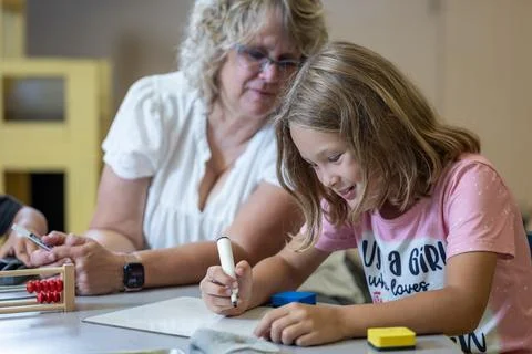 A teacher is helping a child with a math problem Stock Photos