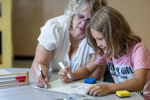 A teacher is helping a child with a math problem Stock Photos