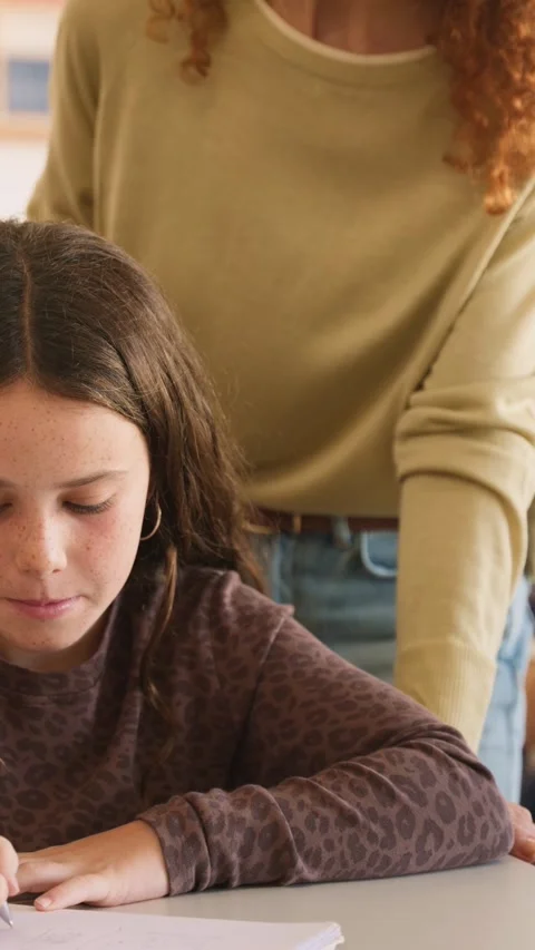 Teacher helping elementary school student with her homework Video stock 345113598