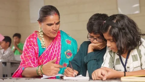 Teacher helping elementary students for writing or solving problems at classroom Stock Footage 201200829