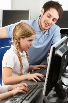 Teacher helping girl using computer in class Stock Photos