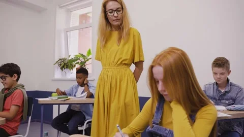 Teacher is helping hardworking students writing a test in elementary school Video stock 162737409