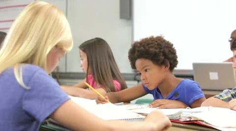 Teacher Helping Male Pupil In Class Stock Footage