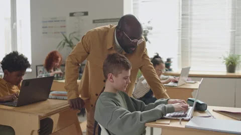 Teacher Helping School Boy with Test during Computer Class Stock Footage 245457262
