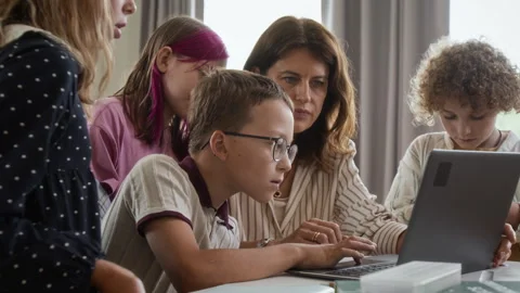 Teacher Helping School Children Using Laptop Computer in Classroom Stock Footage 345213116