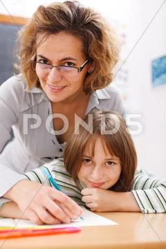 Teacher helping schoolgirl writing Stock Photos