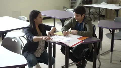 Teacher helping student in classroom Stockbeeldmateriaal 221034408