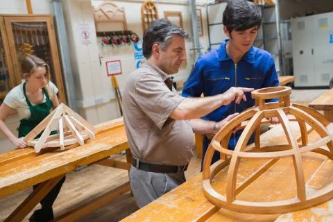 Teacher helping a student in a woodwork class Stock Photos