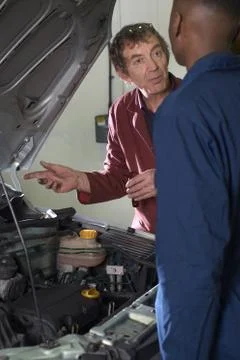 Teacher helping students with car engine 库存照片
