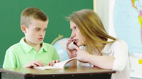 Teacher helping young boy read a book Stock Footage 80131371