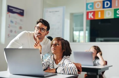 Teacher helping a young student with a coding exercise in a computer litera.. Foto stock