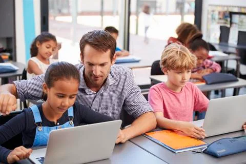 Teacher helping young students using laptops in class 스톡 사진