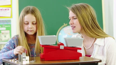 Teacher helping young studeny measure weights Stock Footage 80131562