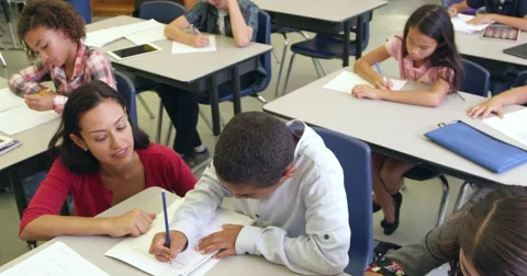 Teacher helps schoolboy in class, elevated zoom, shot on R3D Stock Footage 64407415