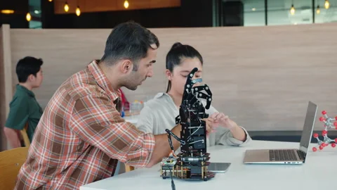 Teacher helps student working on a robotic arm in classroom design and Stock Footage 272709241