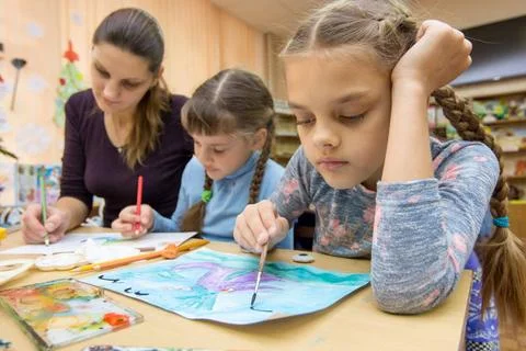 The teacher helps the students in drawing class The teacher helps the stud... Stock Photos
