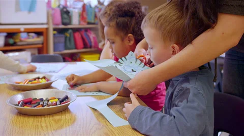 A teacher helps a young student cut the tiger out of his paper artwork Stock Footage 34004755
