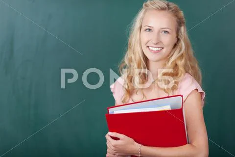 Teacher holding binder against chalkboard Stock Photos