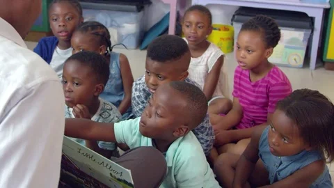 Teacher holds a book for elementary school children to read Stock Footage 78935627