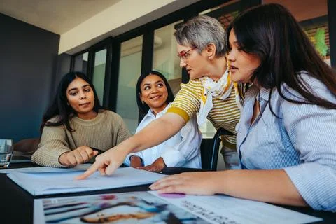 Teacher instructing a diverse group of young women on homework assignment a.. Stock Photos