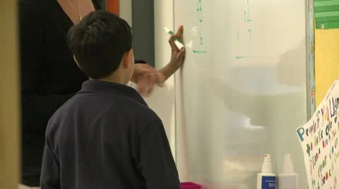 Teacher instructing student writing on white board Stock Footage 8979415