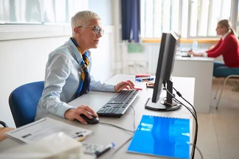Teacher lecturer on class with students working on computer on university. Stock Photos