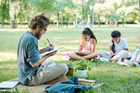 Teacher making notes while students doing tasks Stock Photos