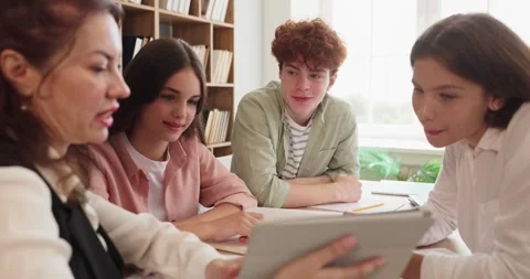 Teacher mentoring teens with tablet in collaborative classroom project Stock Footage 338289540