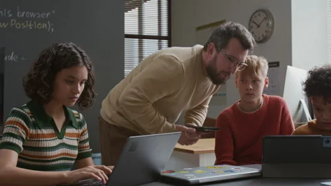 Teacher Observing Students Writing Computer Code and Giving Advice Stock Footage 318714994