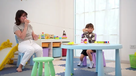 Teacher or parent communicating with a child through pretend phone play Video stock 339564930