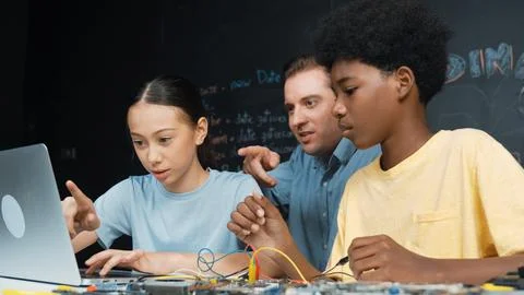Teacher pointing at laptop while teaching about engineering code. Edification. Stock Photos