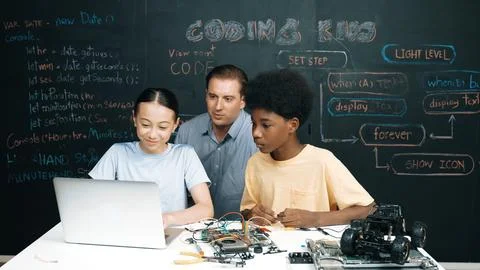 Teacher pointing at laptop while teaching about engineering code. Edification. Stock Photos