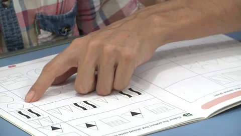 The teacher points to the geometric shapes in the book and explains how to c Stock-Footage 150252545
