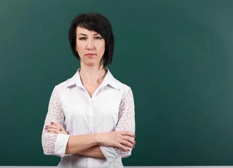 Teacher posing by chalk Board, learning concept, green background, Studio sho Stock Photos