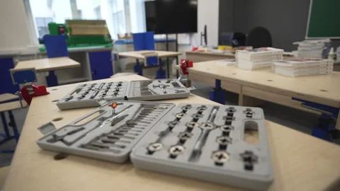 Teacher puts toolboxes on desks before practical lesson Видео 310774058