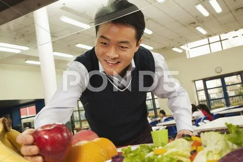 Teacher reaching for healthy food in school cafeteria Stock Photos