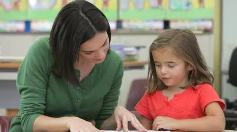 Teacher Reading Book With Female Pupil Stock Footage