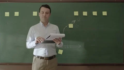 The teacher is reading reports in front of a green blackboard. Stock Footage 201296421