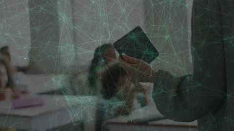 Teacher reading tablet while scanning classroom and pointing at boy raising hand Stock Footage 311519024