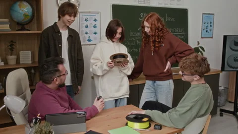 Teacher Showing 3D-Printed Model to Four Students Around his Classroom Table Stock Footage 335696208