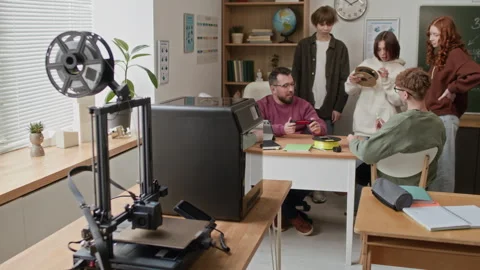 Teacher Showing 3D Printed Part to Students Gathered Around his Table in Class Stock Footage 335693672