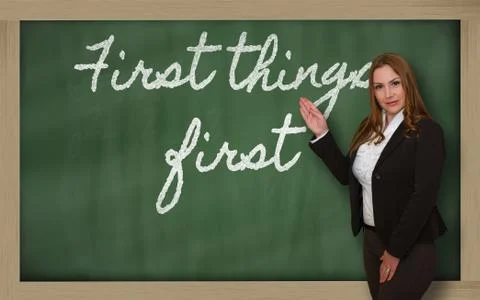 Teacher showing first things first on blackboard Stock Photos