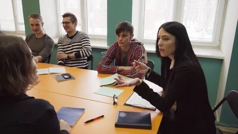 Teacher sits at a table and talks with students at university Stock Footage 86493882