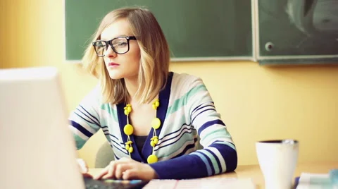 Teacher sitting in the class and working on computer 스톡 동영상 61190567