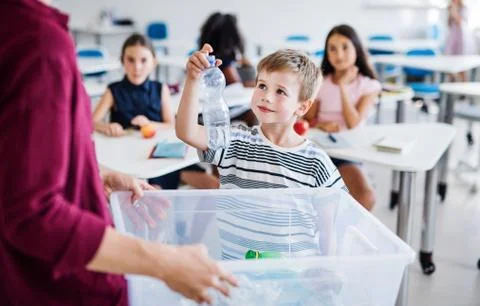 A teacher with small school kids in classroom learning about waste separation. Stock Photos