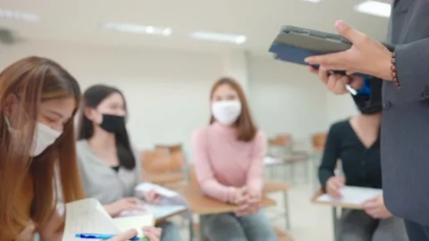 A teacher with a tablet teaches students in the classroom at the university.  Stock Footage 147957120