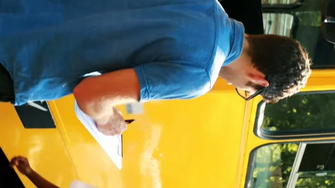 Teacher taking attendance while student entering in bus Stock Footage 301361278